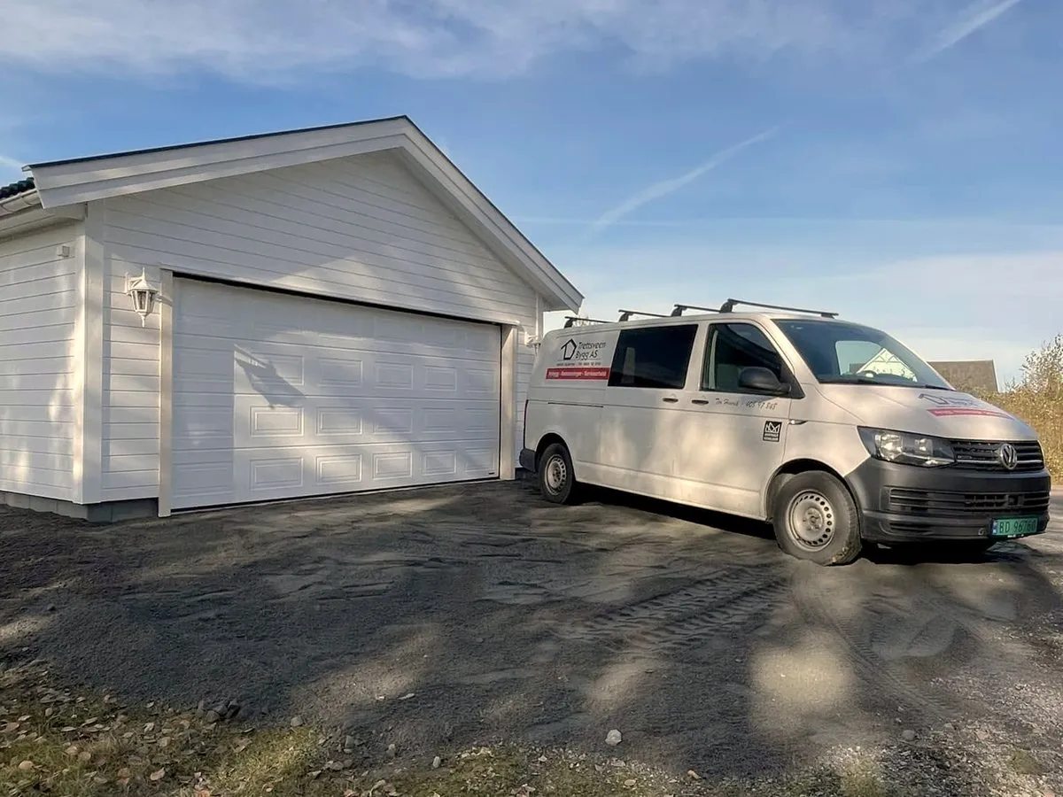 Ny garasje med hvit kledning og firmabil foran